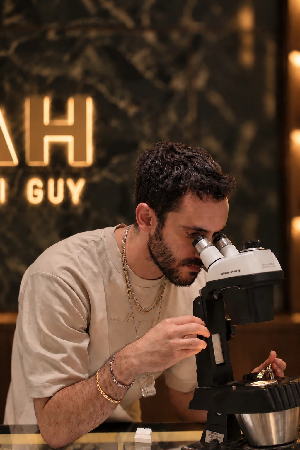 Avi examining a green gemstone under a gemological microscope at the showroom counter