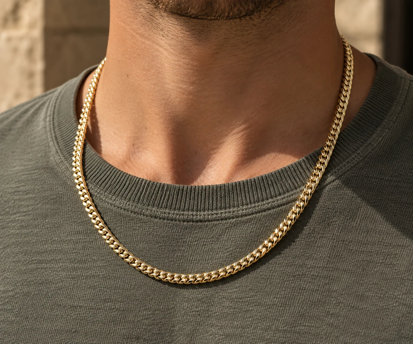 Gold Cuban link chain worn over a grey t-shirt