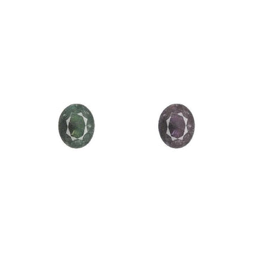 Two oval alexandrite gemstones, faceted, showing green and purple hues