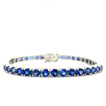 Blue sapphire tennis bracelet with silver-toned links and hinged clasp