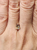 Triangular bi-color sapphire shown on a finger to indicate its small size