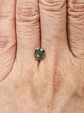 Oval olive green demantoid garnet shown on a hand for scale