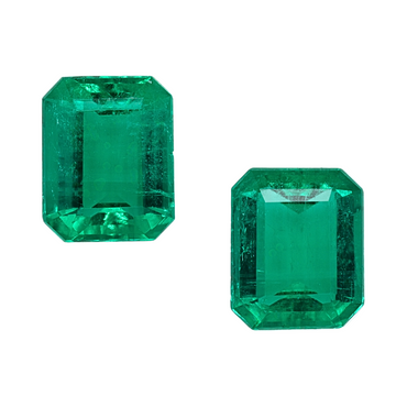 Two emerald-cut green emerald gemstones with rectangular step facets