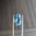 Oval blue aquamarine gemstone in silver prong setting, angled full view