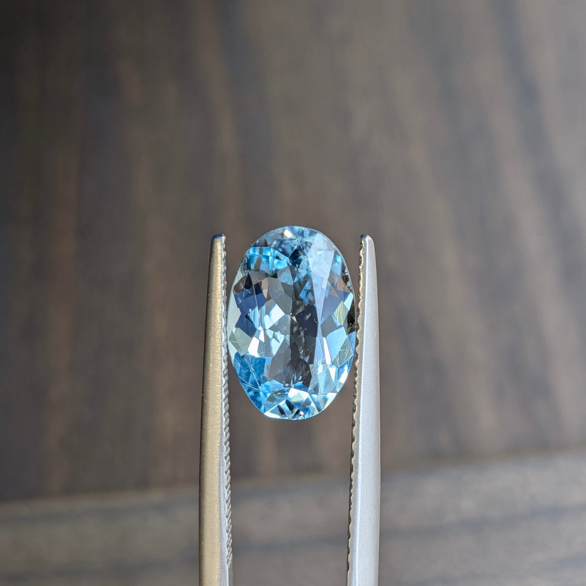 Oval blue aquamarine gemstone in silver prong setting, angled full view