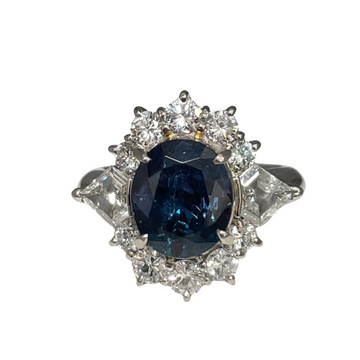 Platinum ring with blue oval center gemstone and diamond side accents