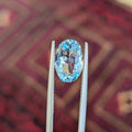 Oval blue aquamarine gemstone in silver prong setting, close-up view