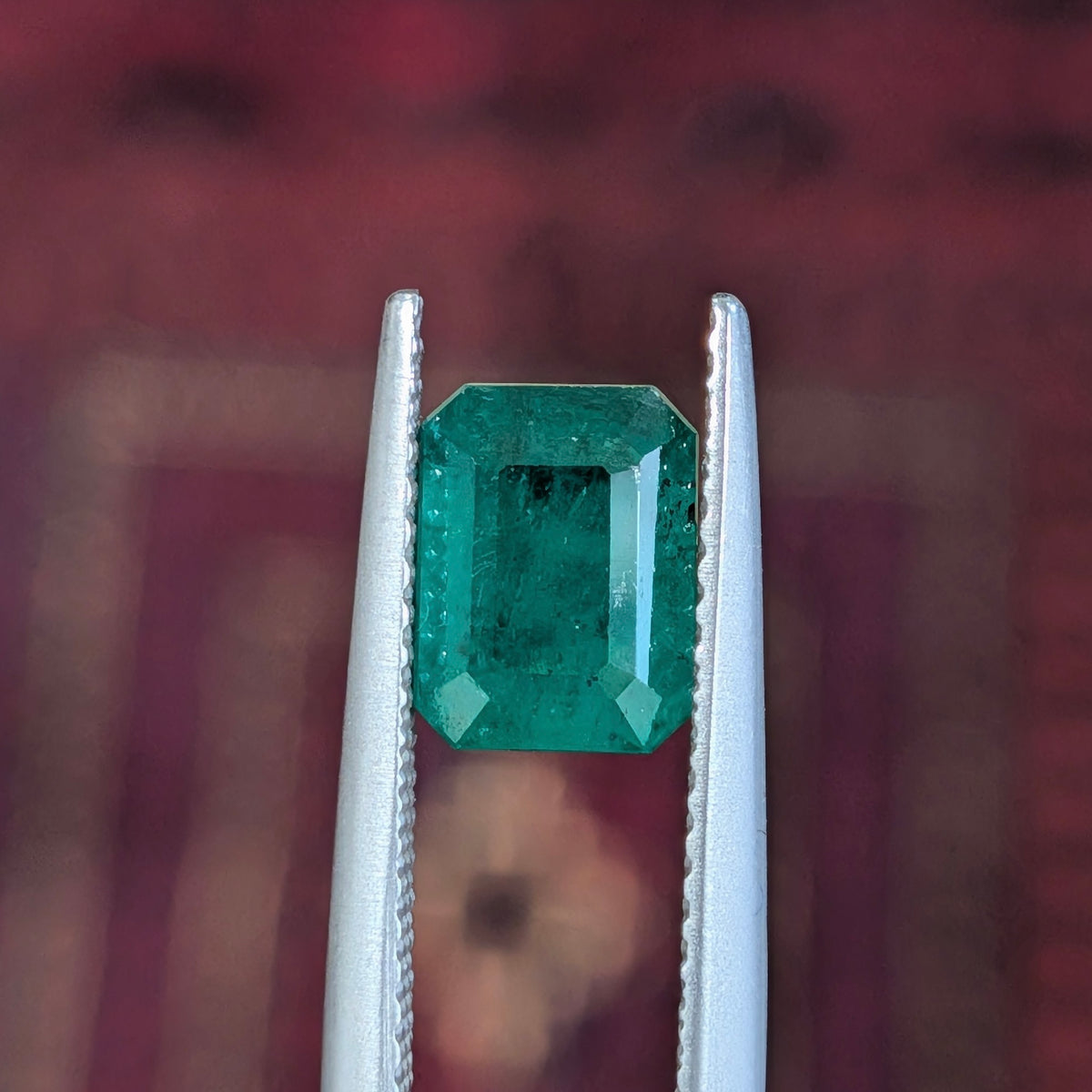 Emerald-cut green gemstone in four-prong style metal setting