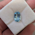 Oval blue aquamarine gemstone on white display pad