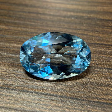 Oval blue aquamarine gemstone with faceted surface, standalone