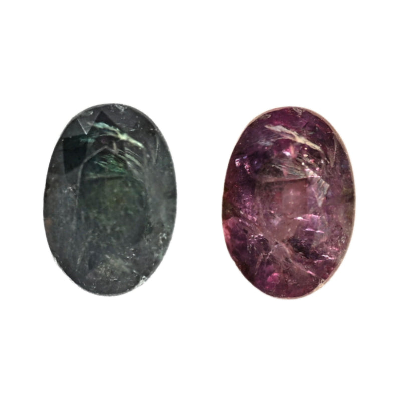 Two oval alexandrite gemstones with faceted surfaces: dark green and deep purple.