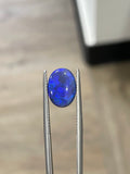 Oval blue boulder opal gemstone in two prong settings, close-up