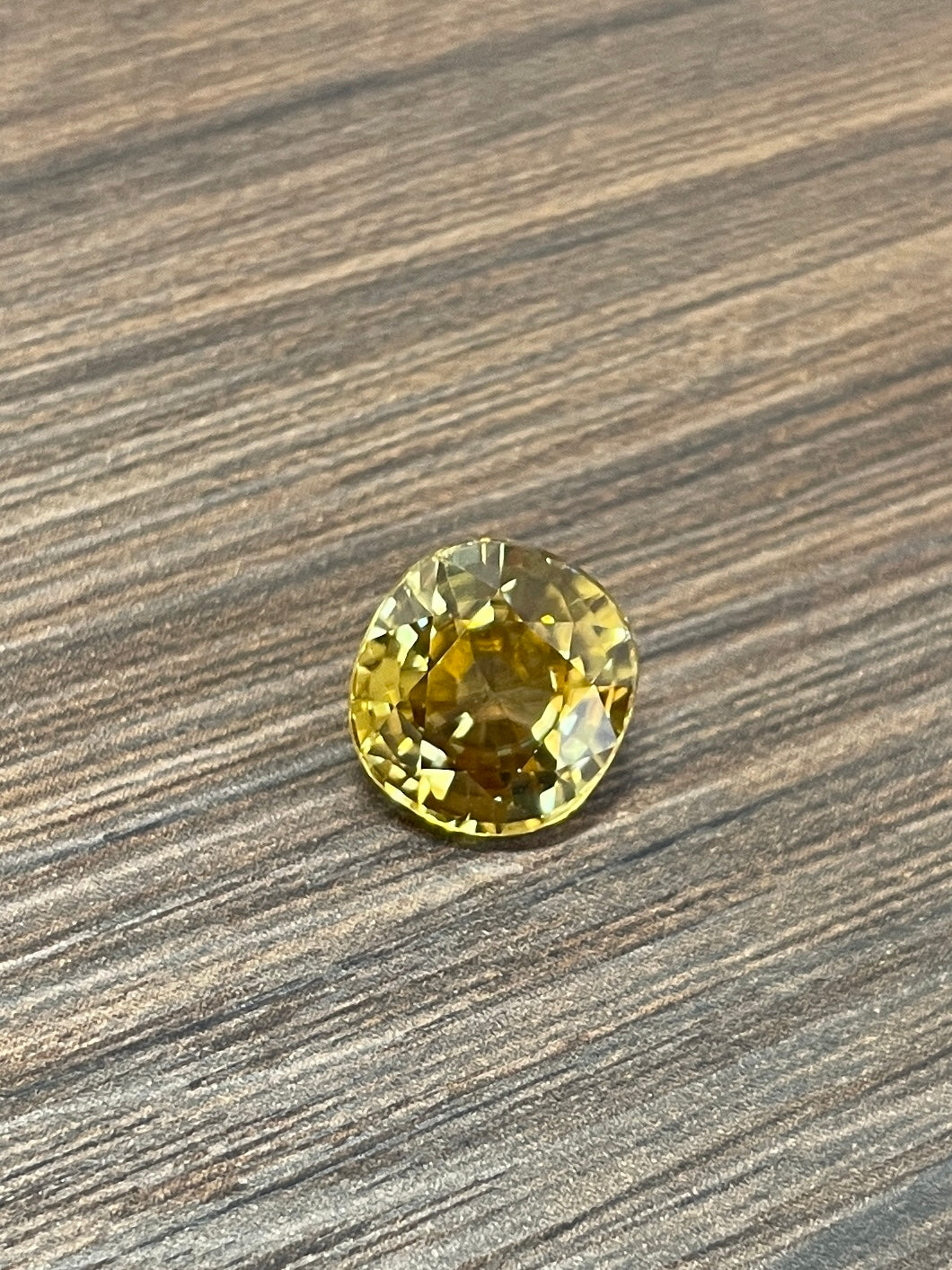 Round yellow zircon gemstone on wood surface