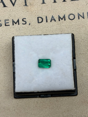 Emerald-cut green gemstone in a black display box