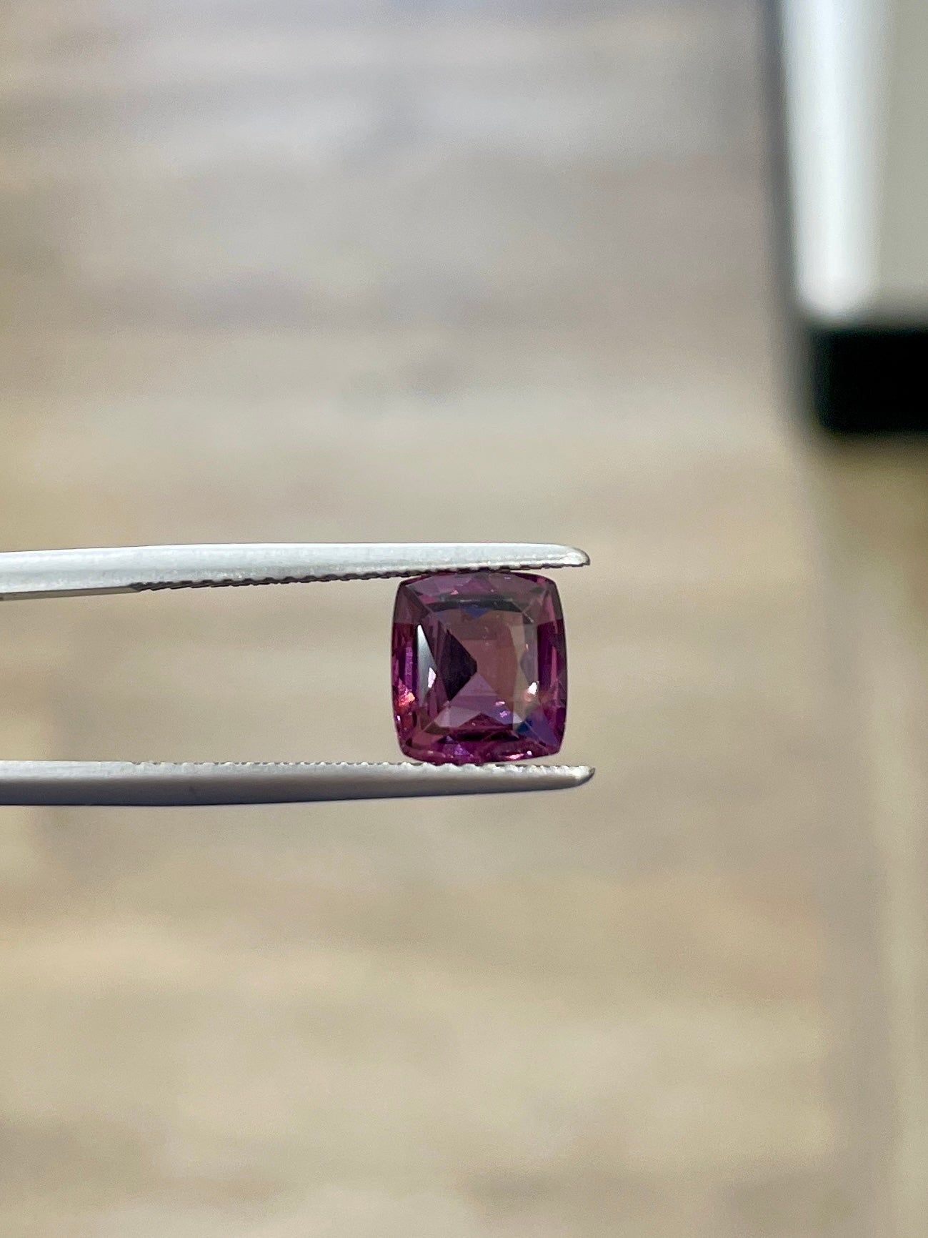2.45ct purple cushion-cut spinel gemstone in tweezers