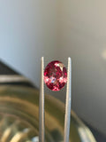 Faceted oval pink color-change garnet gemstone between metal prongs
