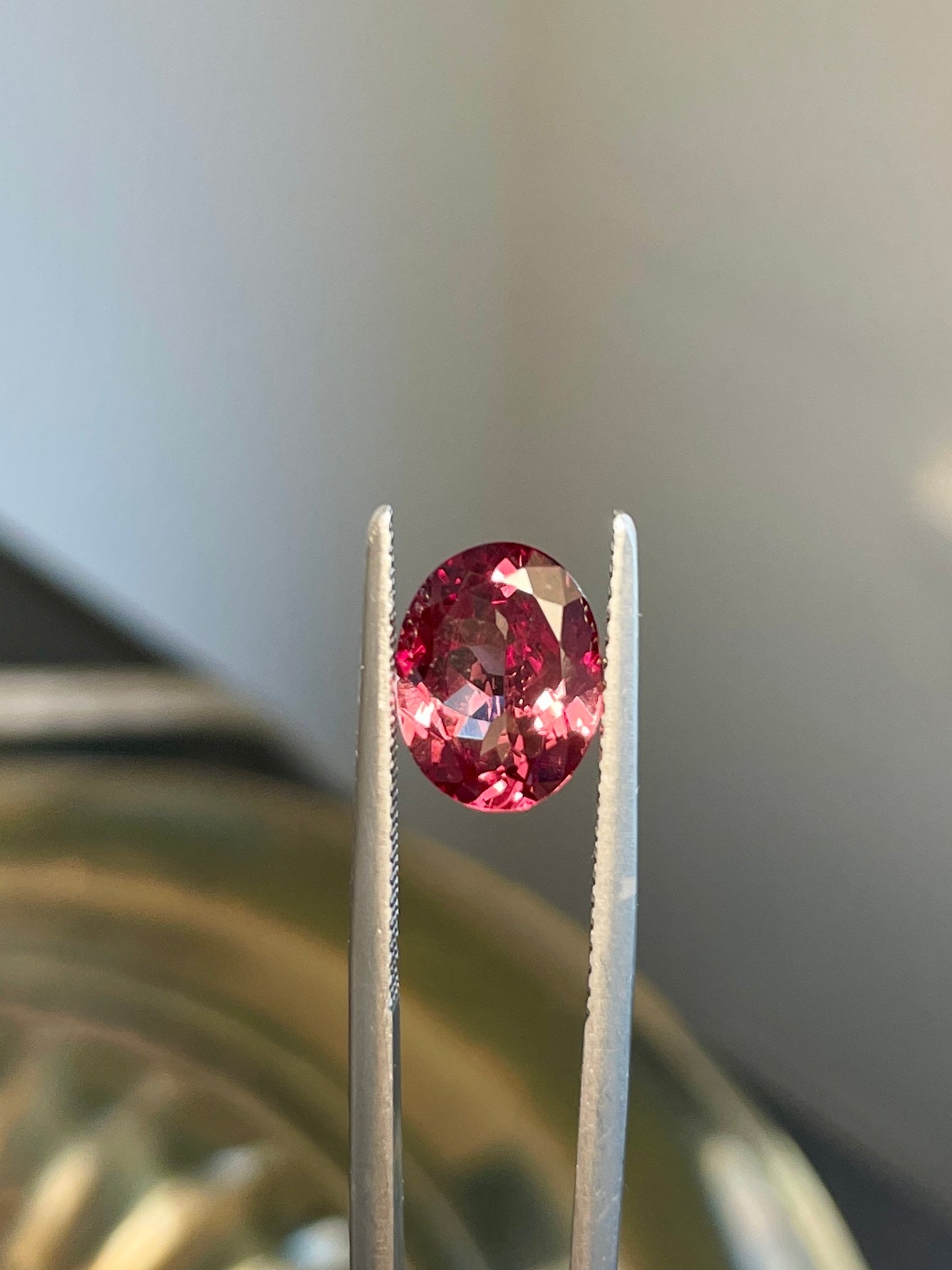 Faceted oval pink color-change garnet gemstone between metal prongs