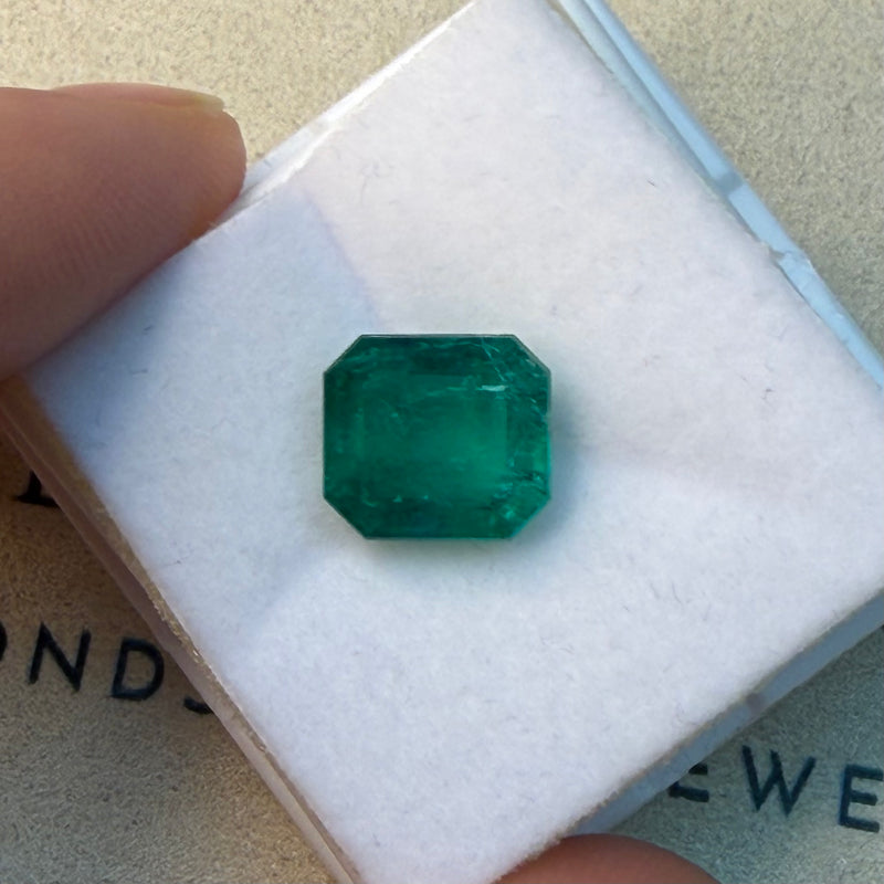 Faceted octagonal green emerald gemstone, loose stone on display card