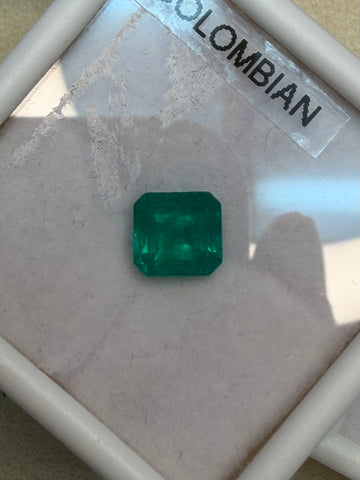 Vivid green emerald gemstone, rectangular step-cut, in display box