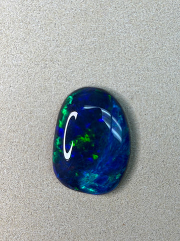 12.60-carat black opal with vivid blue and green iridescence, oval cabochon