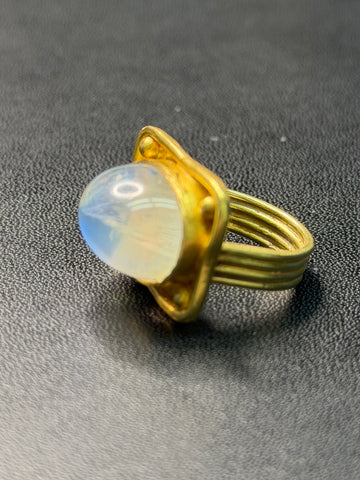 Oval moonstone cabochon ring with 19k gold bezel and three-band style shank