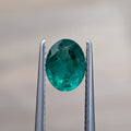 Oval green emerald gemstone in silver prongs, oval cut, 0.92 ct