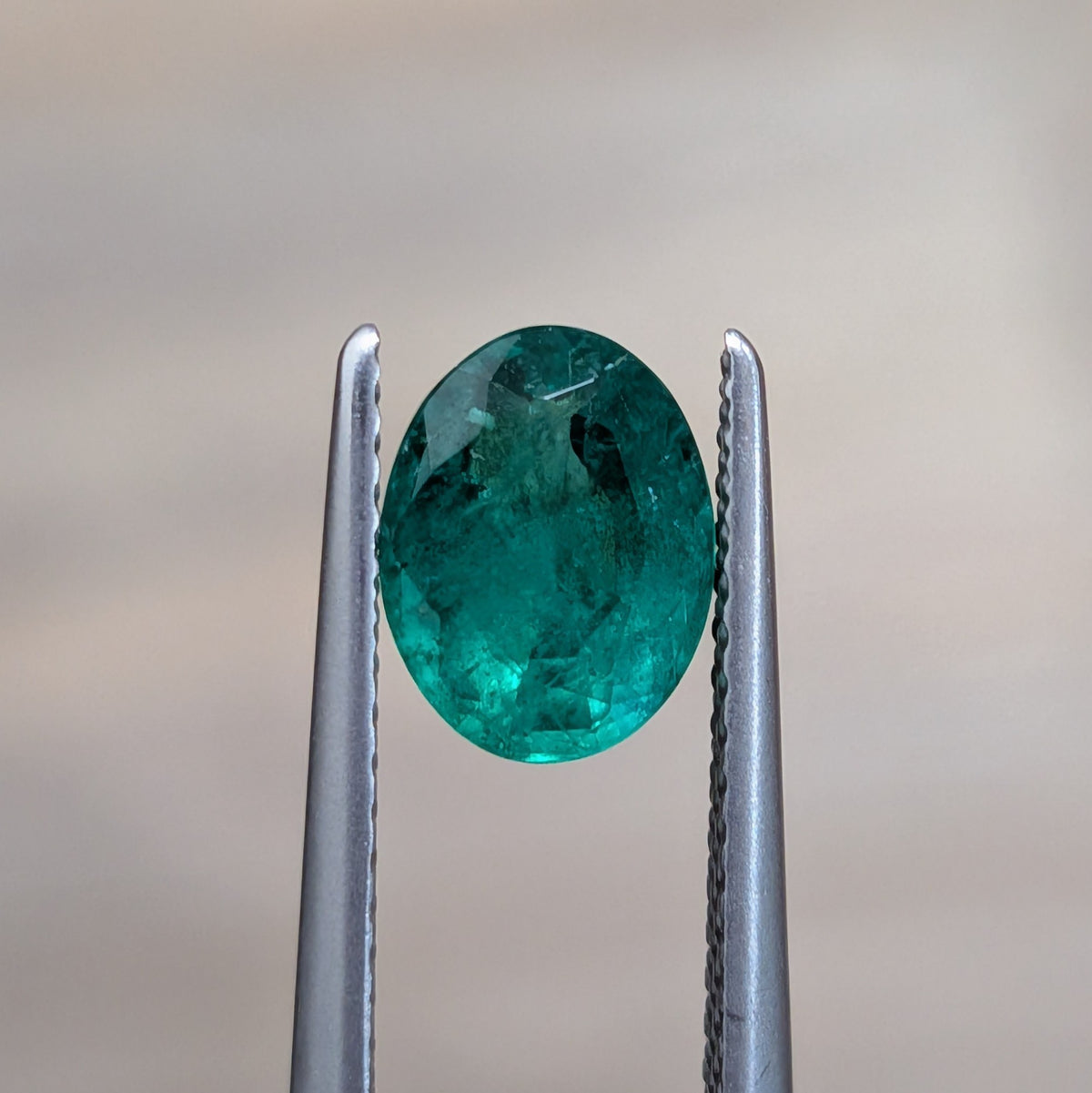 Oval green emerald gemstone in silver prongs, oval cut, 0.92 ct