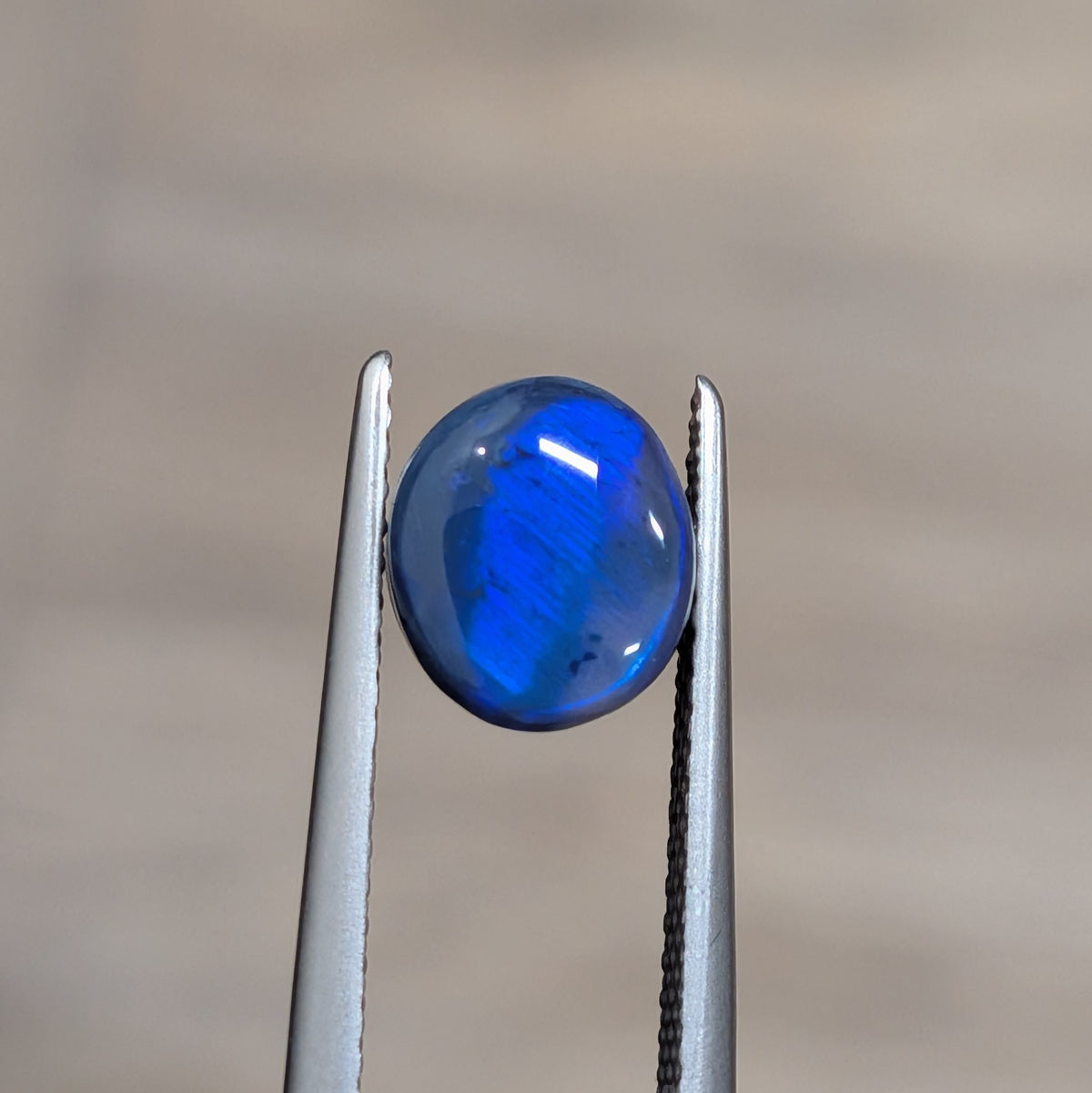 Oval blue opal cabochon in silver prong setting