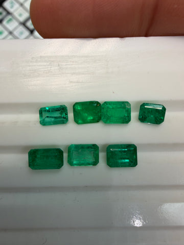 7 emerald-cut green emerald gemstone lot on a display tray