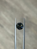 Round dark green sapphire gemstone in a prong setting between two metal posts
