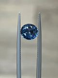 Round blue spinel gemstone held by prongs in a metal setting