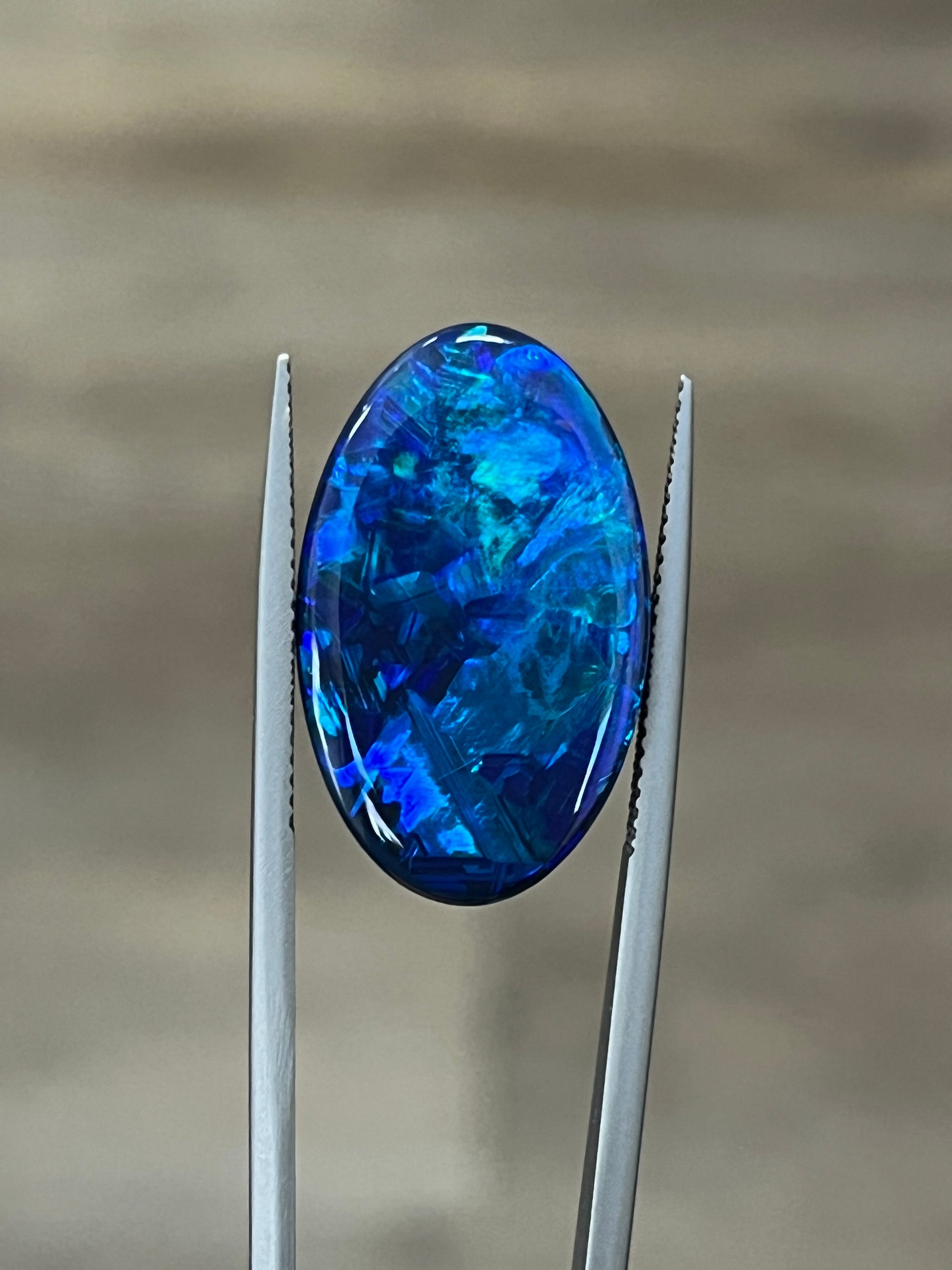 Oval blue opal cabochon gemstone set in two metal prongs