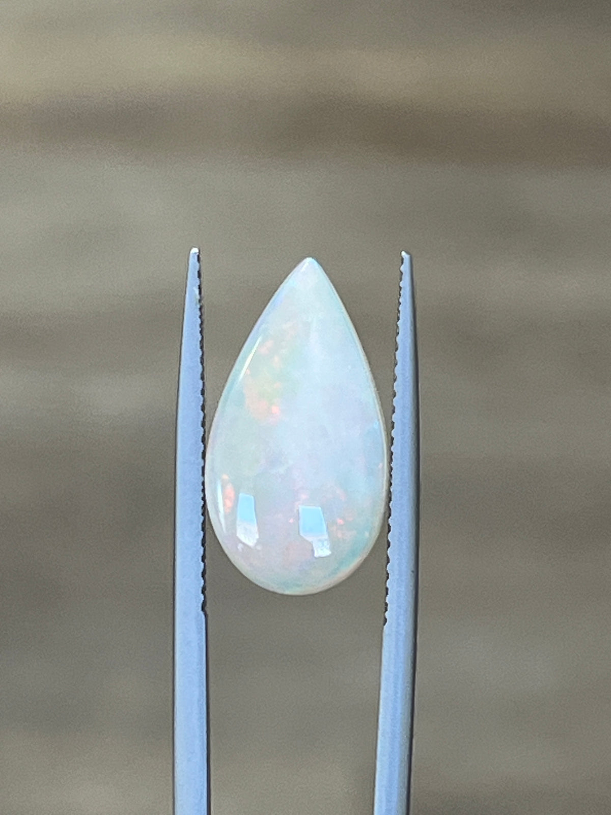 3.27-carat white opal teardrop cabochon between metal prongs