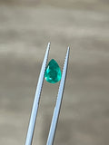 Teardrop emerald gemstone in white metal prongs, bright green
