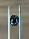 Teal sapphire gemstone set between two metal prongs