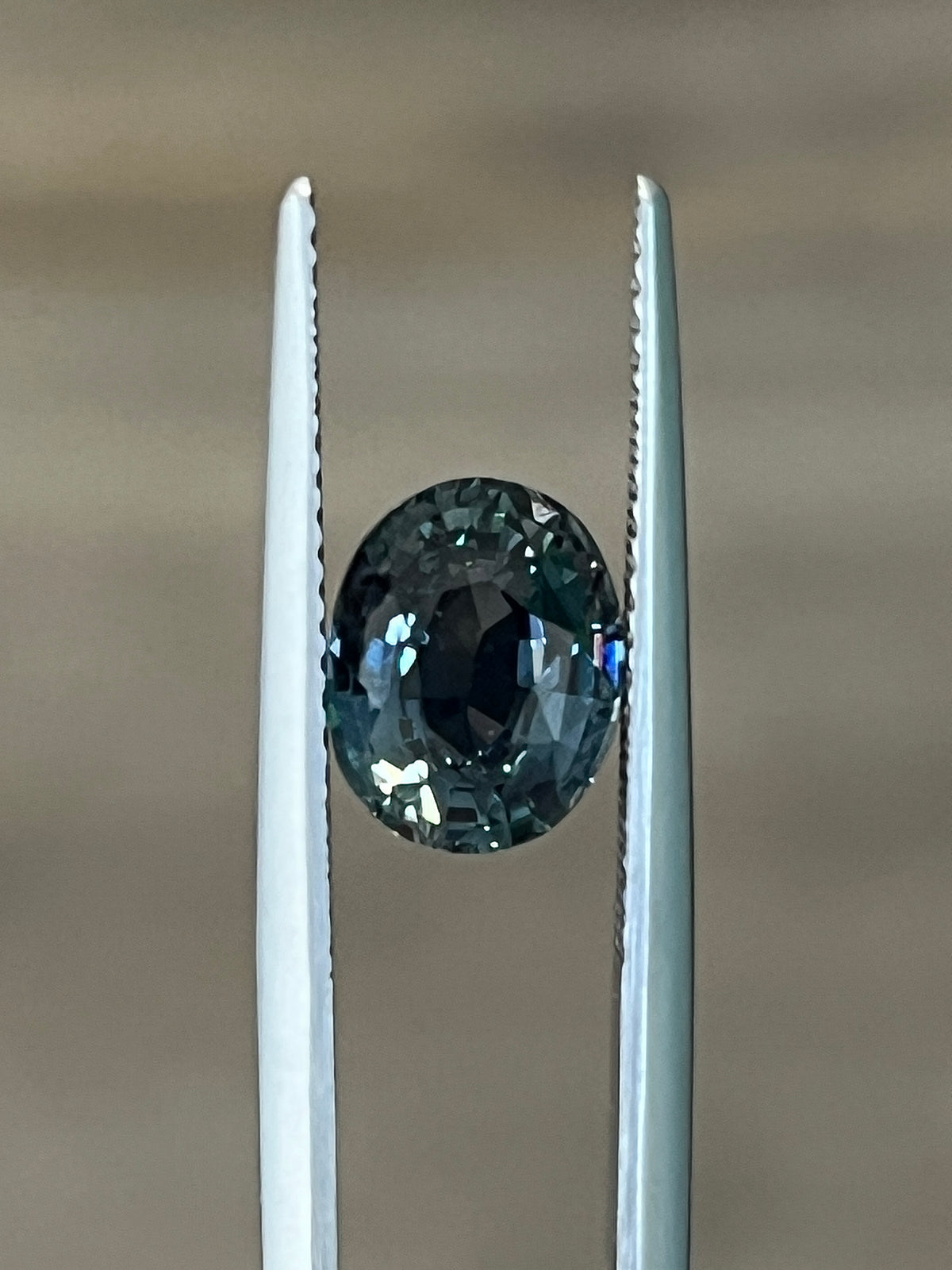 Teal sapphire gemstone set between two metal prongs
