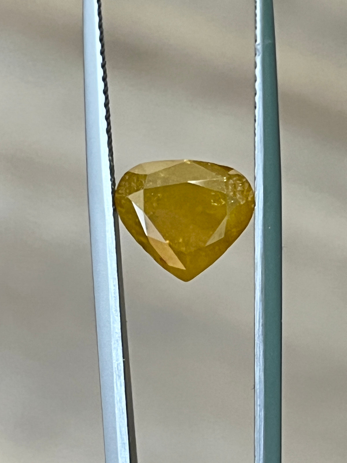 Faceted yellow-brown diamond in display tray, close-up