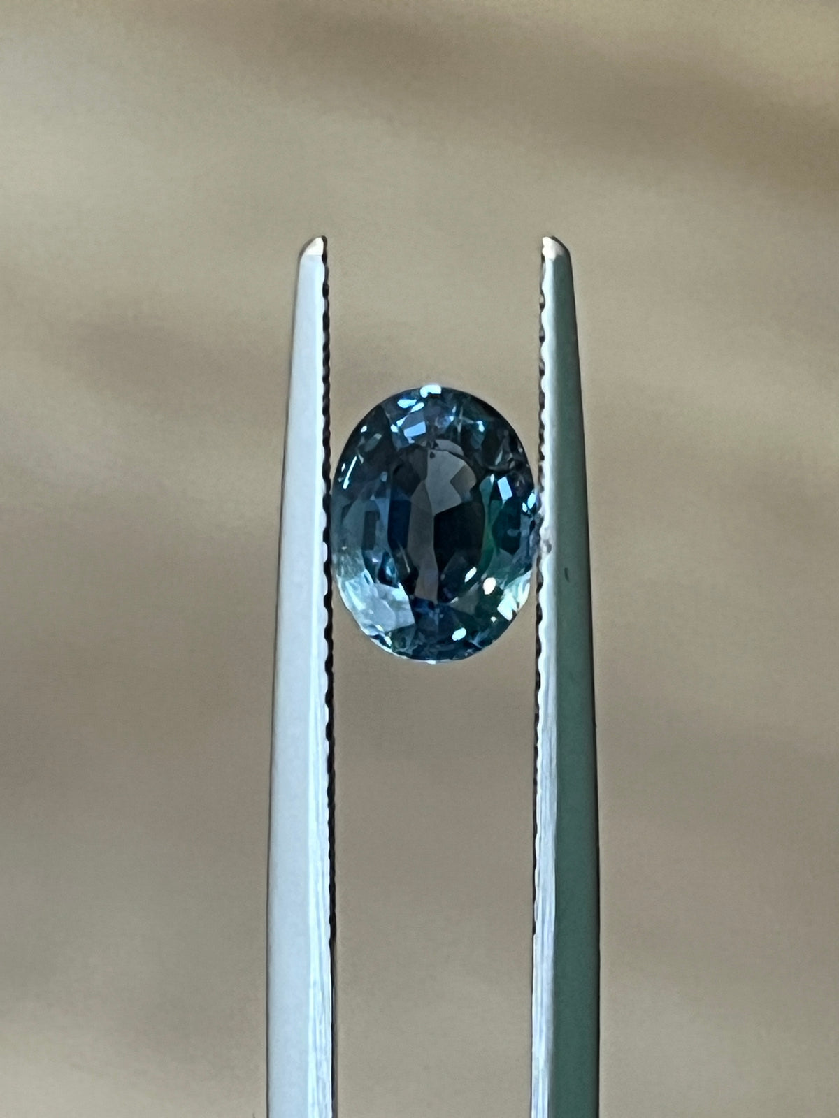 Light-blue oval sapphire gemstone held by two metal prongs