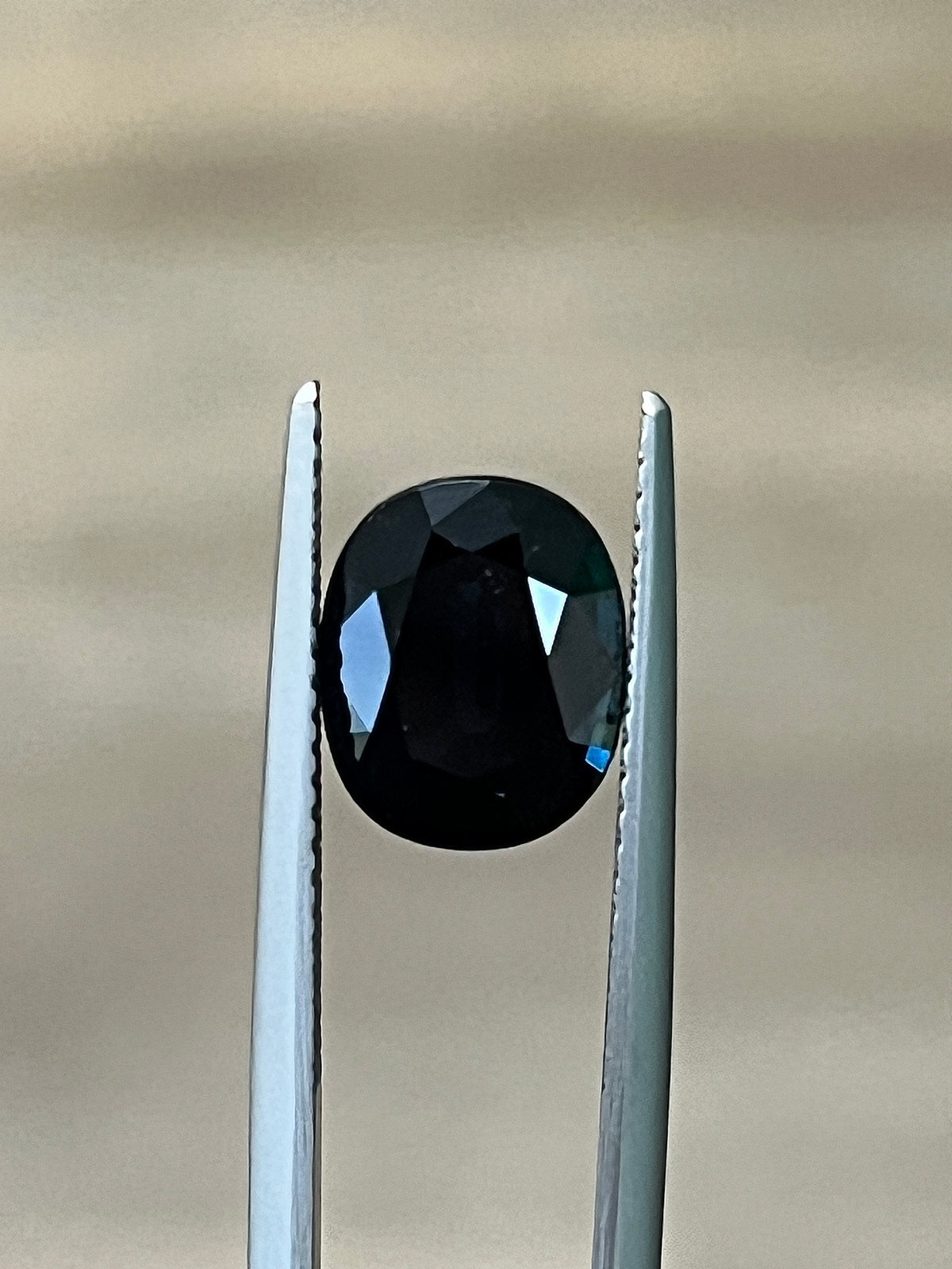 3.10-carat dark gemstone with two metal prongs, oval faceted center
