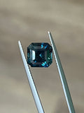 Teal octagonal step-cut sapphire between tweezers