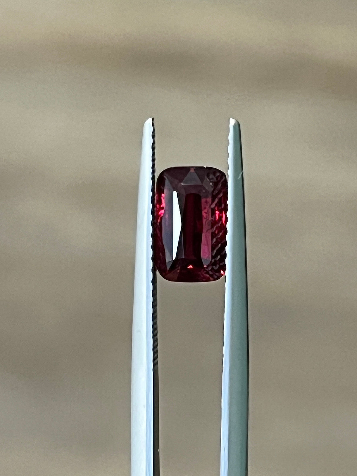 Red ruby gemstone held between two metal prongs in a rectangular setting