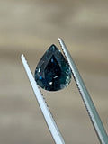 Teal pear-cut sapphire gemstone held in metal prongs