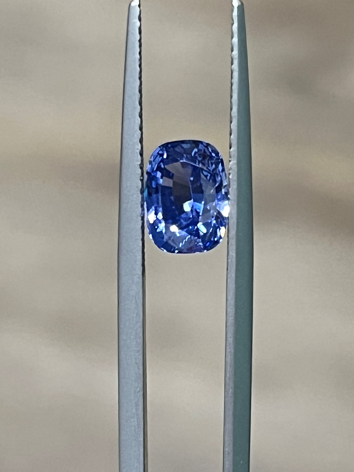 Blue sapphire gemstone in metal prong setting, close-up