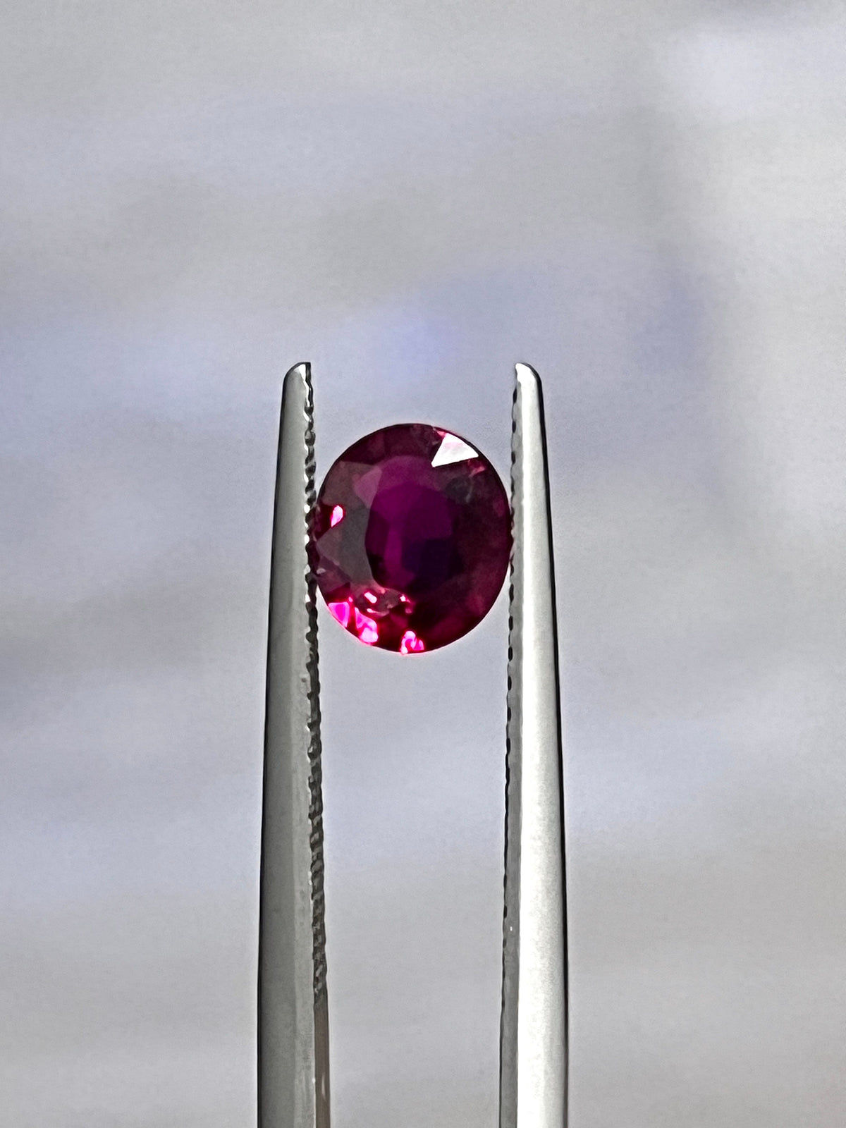 Oval ruby gemstone in silver prongs setting, bright red
