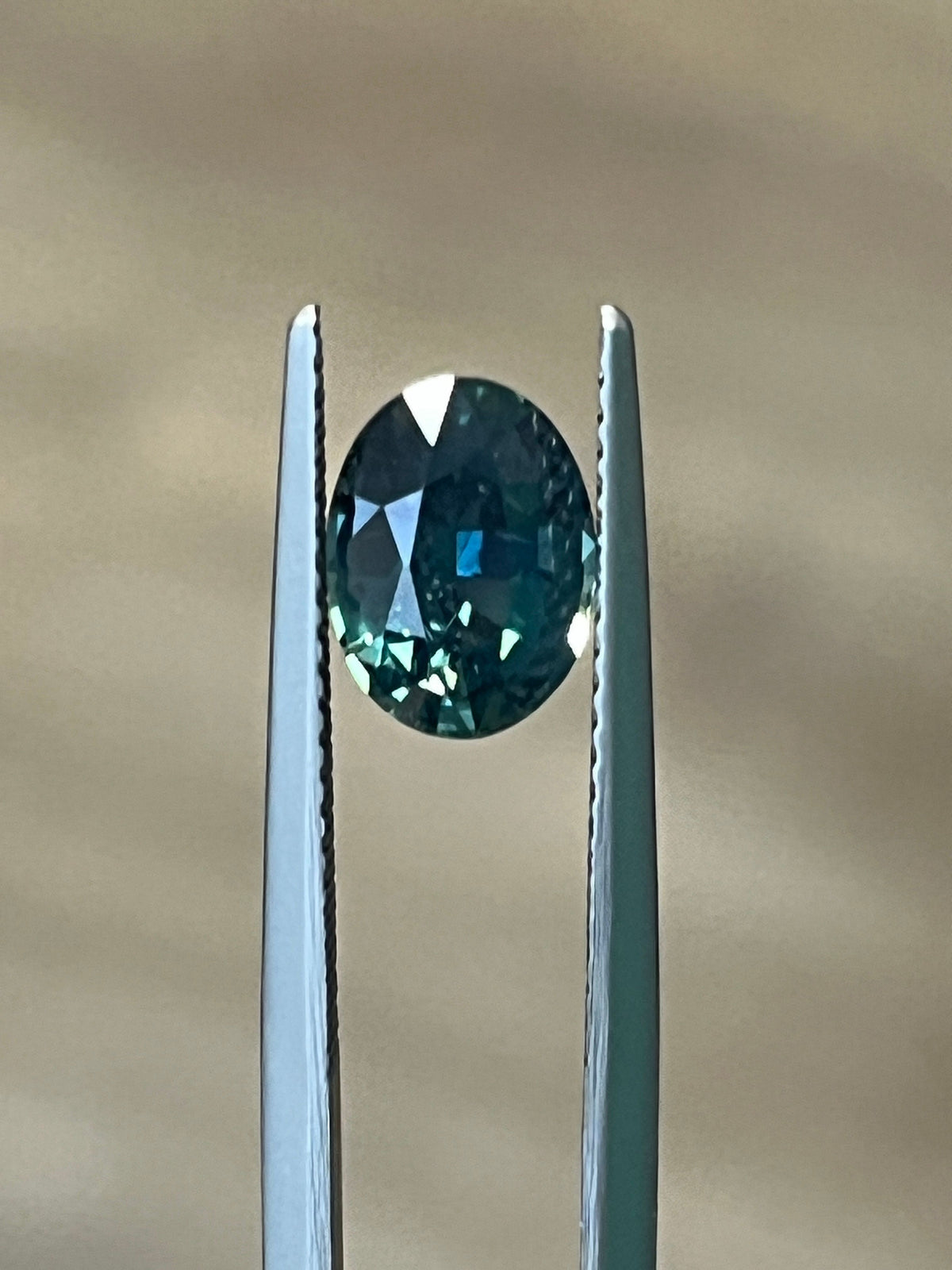 Oval-cut no-heat sapphire held in tweezers