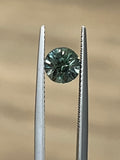 Round green sapphire held in tweezers, showing its faceted cut