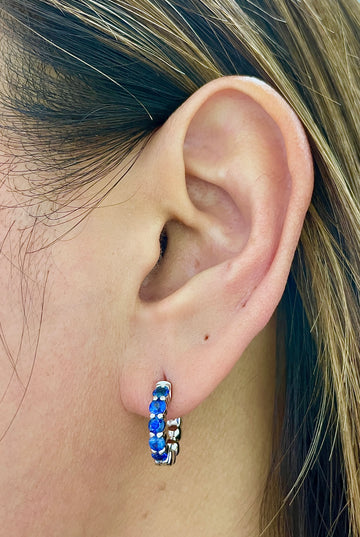 Sapphire mini hoop earrings with blue gemstone bands, silver-tone hoops on ear