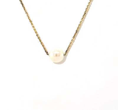 Single round pearl pendant on 14k yellow gold chain, close-up