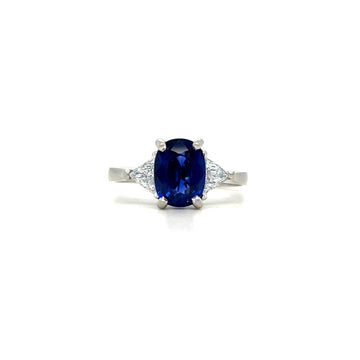 Platinum ring with oval dark blue sapphire and small diamond accents on shoulders