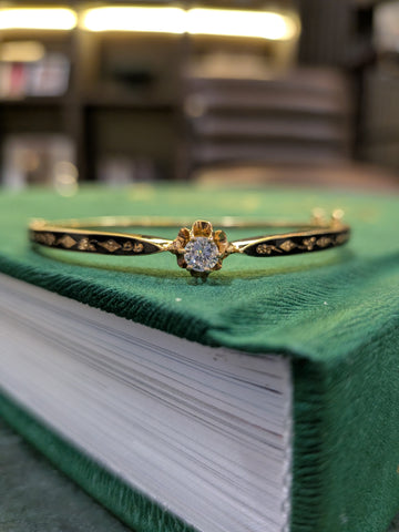 14k yellow gold enamel diamond bangle centered on green fabric, round diamond centerpiece